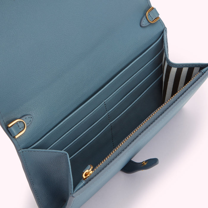 Dusty blue leather wallet open to show multiple card slots and a zippered coin compartment, with a black and white striped fabric lining.