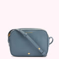 A dusty blue Lulu Guinness crossbody bag with gold hardware.