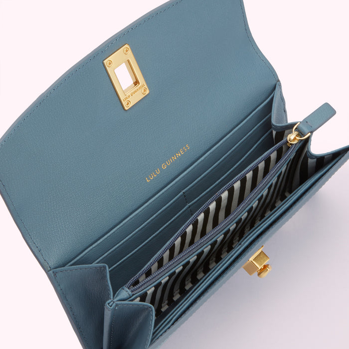 Open blue Lulu Guinness wallet with gold hardware and black and white striped interior.