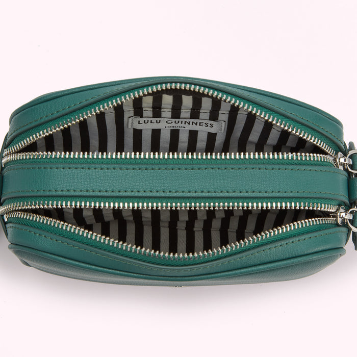 Open dark teal Lulu Guinness crossbody bag with black and white striped interior lining.