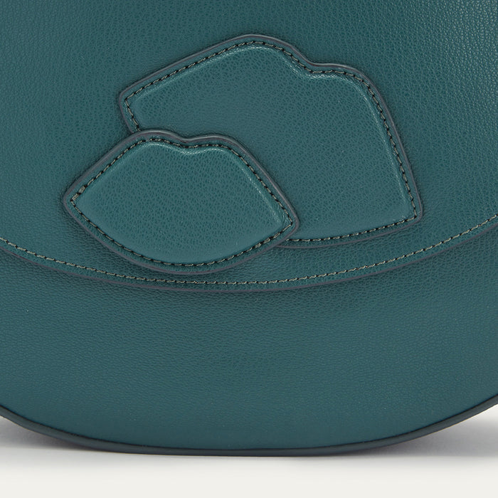 Teal leather handbag with a lip shaped applique patch on the front and silver printed 'Lulu Guinness' logo on a white background