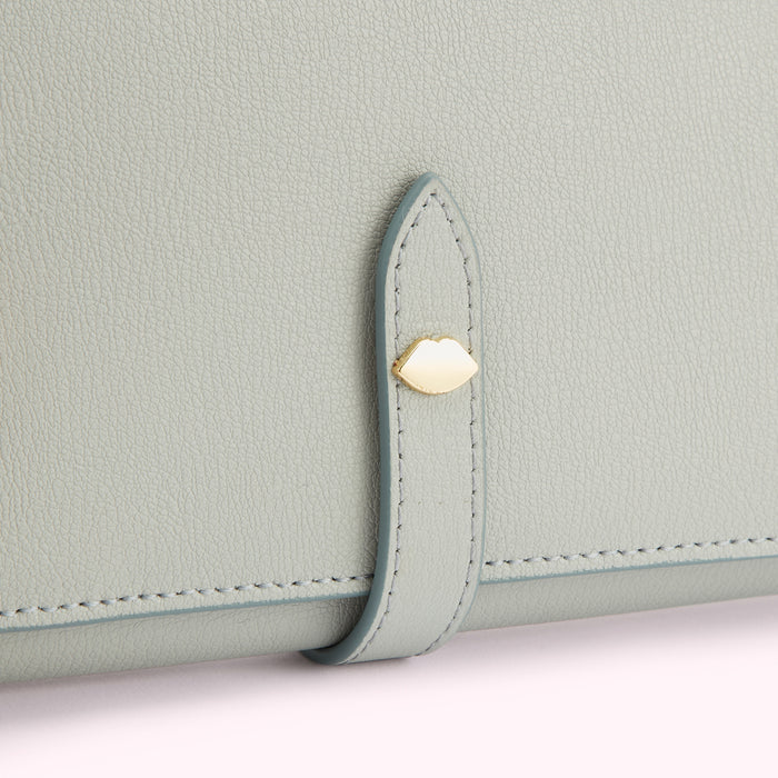 Close-up of a light grey leather wallet with a gold clasp.