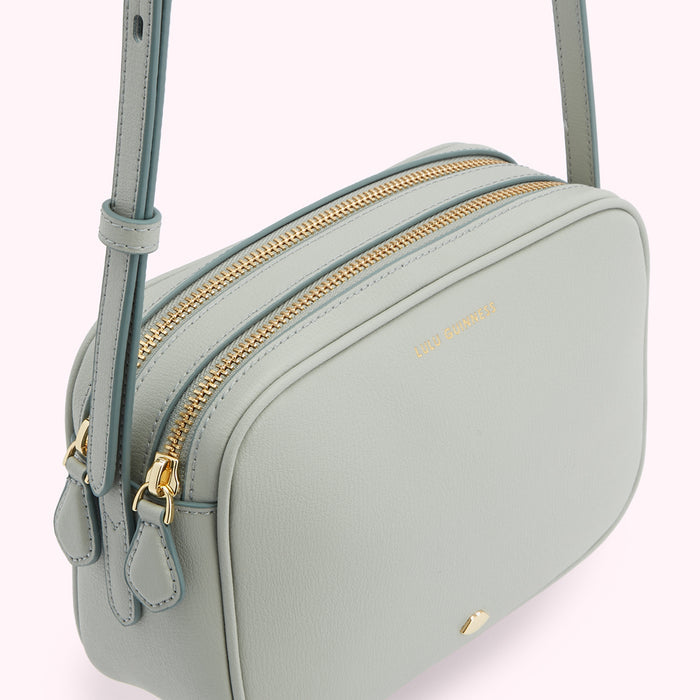 Sage green Lulu Guinness crossbody bag with gold zippers.