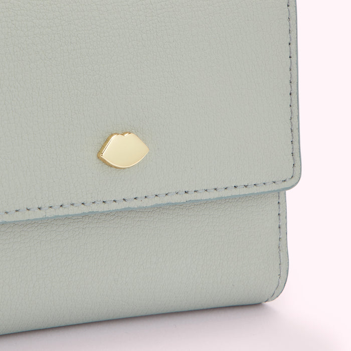 Close-up of a light grey leather wallet with a gold lip-shaped detail.