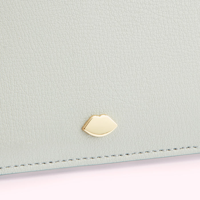 Close-up of a light grey leather wallet with a gold lip-shaped detail.