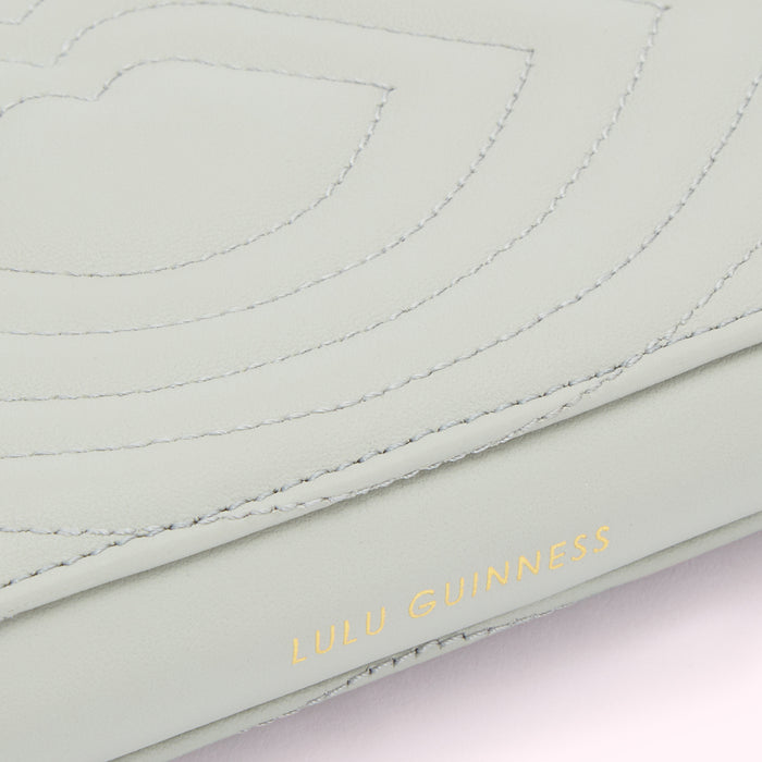 Close-up of a pale green Lulu Guinness bag showing textured leather and stitching detail.