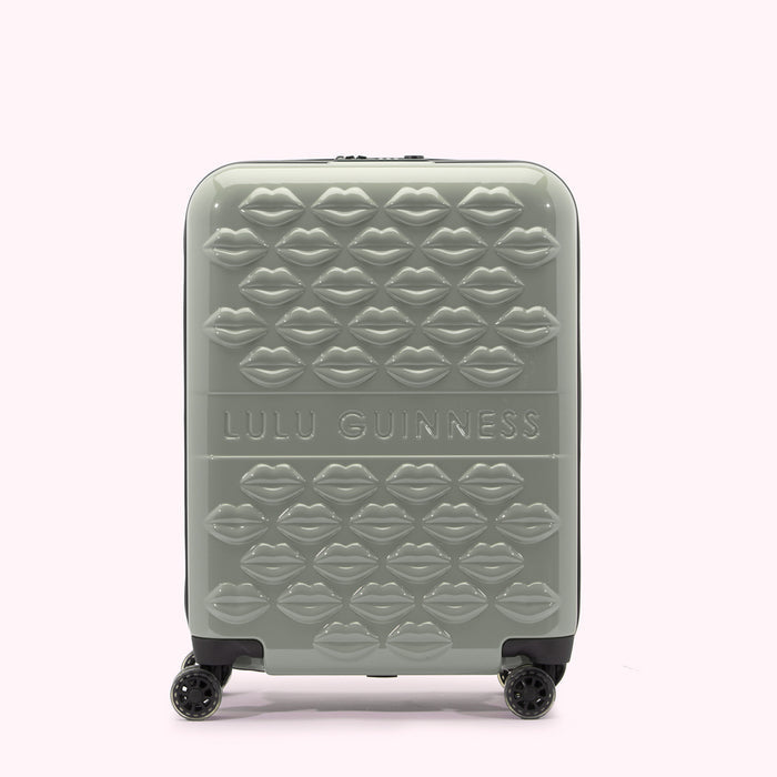 Sage green Lulu Guinness suitcase covered in a pattern of embossed lips.