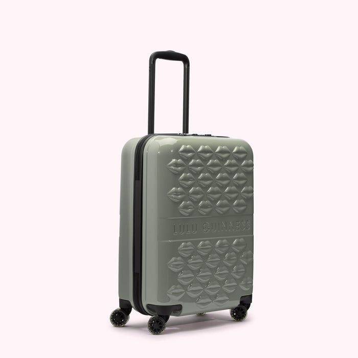 Sage green Lulu Guinness suitcase with a lip pattern.