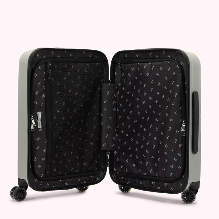 A light grey carry-on suitcase open to reveal its black interior with zippered compartments and a repeating pattern.