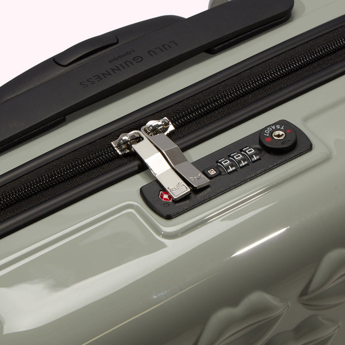 Close-up of a sage green Lulu Guinness suitcase showing the TSA-approved combination lock and zipper.