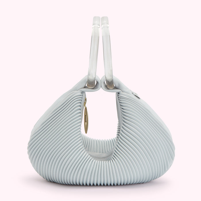 Light blue pleated handbag with clear handles and gold detail.