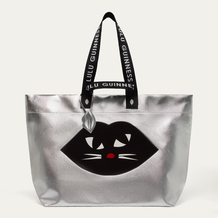 Silver tote bag with black cat design and Lulu Guinness handle on a white background