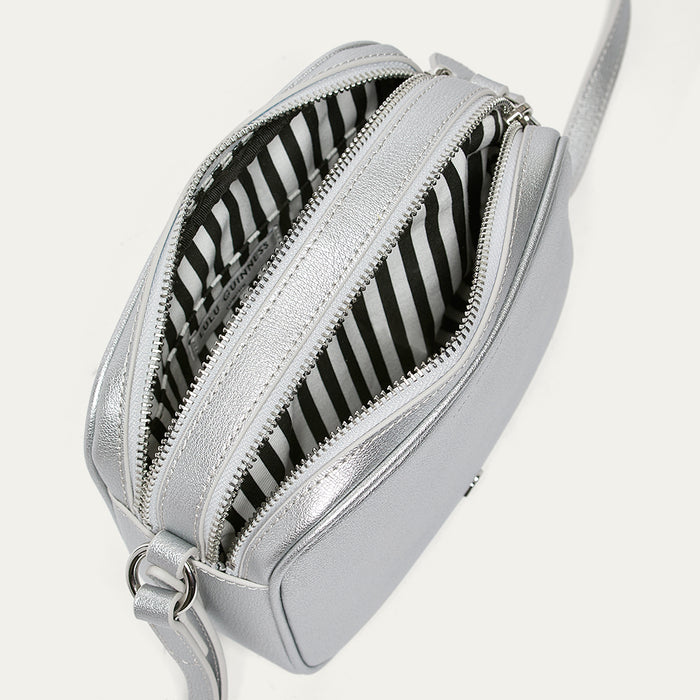 Silver crossbody bag open revealing a black and white striped lining on a white background