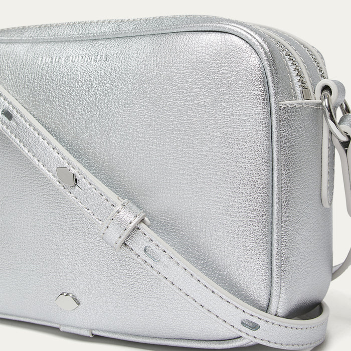 Close-up image of a silver crossbody bag with a strap on a light gray background
