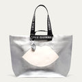 Silver tote bag with a white lip design and Lulu Guinness strap on a light gray background