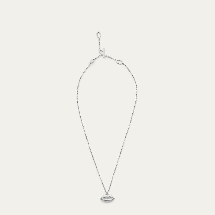 Silver necklace with a lip shaped pendant with a crystal design on a light gray background