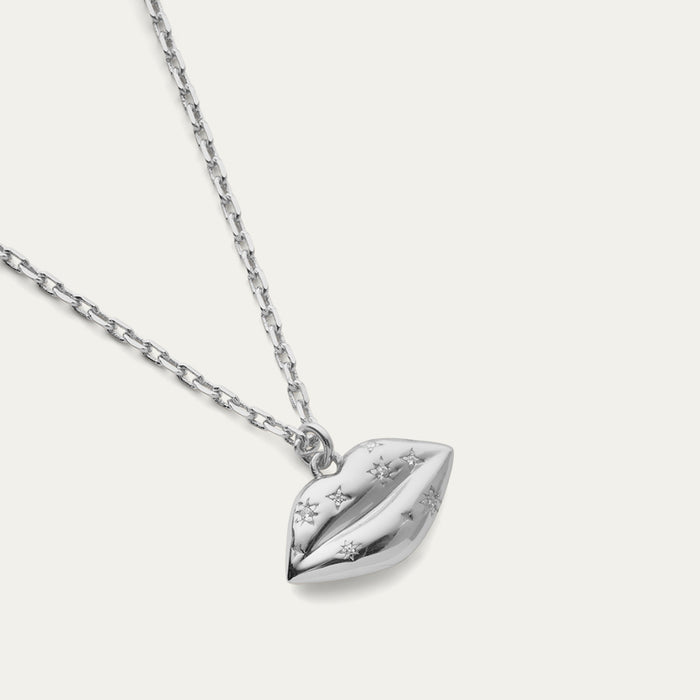 Silver necklace with a lip-shaped pendant with a crystal design on a light gray background