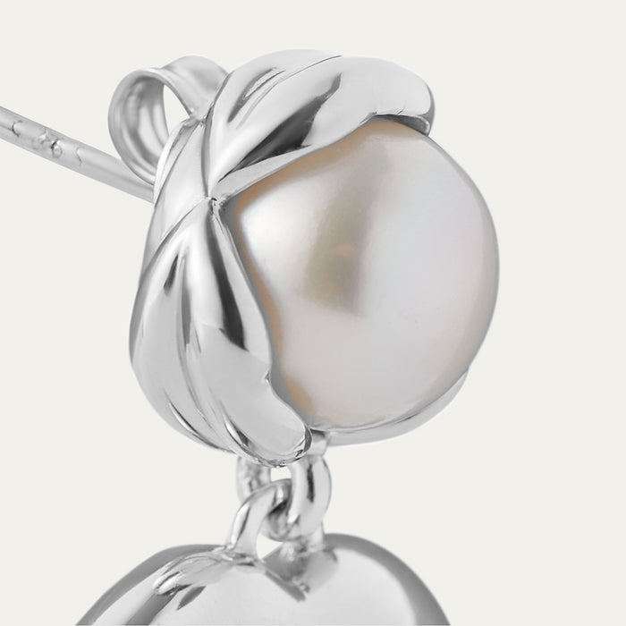 Silver earring with a pearl-like bead on a white background