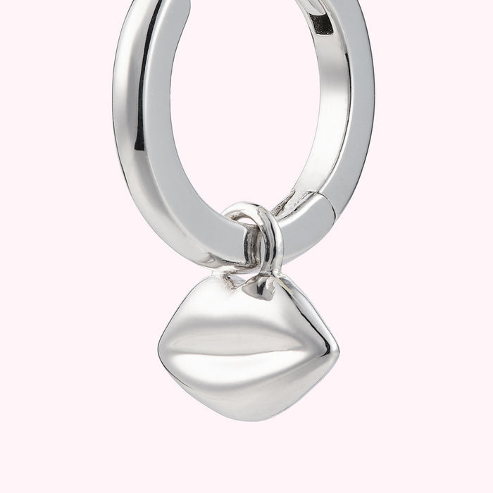 Close up image of a sterling silver hoop earring with lip charm.