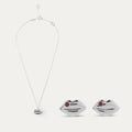 Silver lip-shaped pendant and stud earrings with red stones on a white background