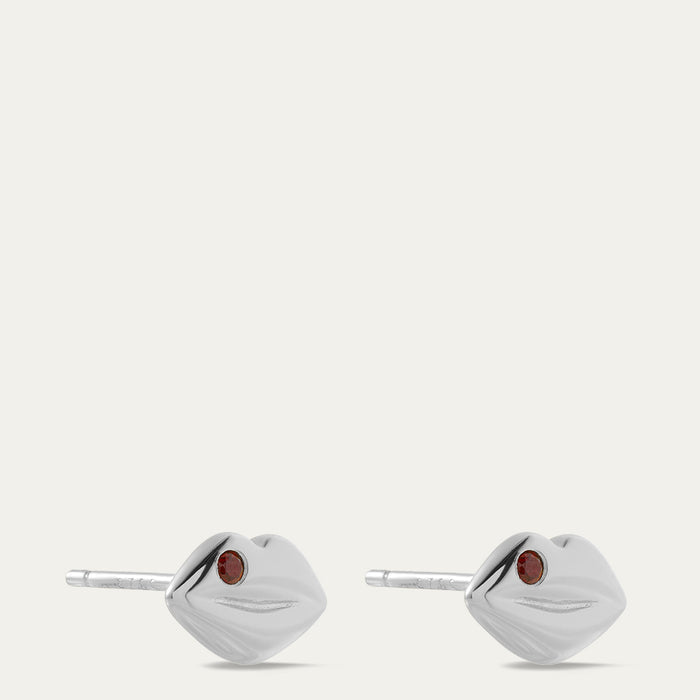 Pair of silver lip-shaped earrings with red gemstones on a white background