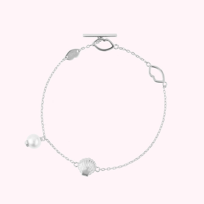 Sterling silver bracelet with shell and freshwater pearl charms and lip shaped links.