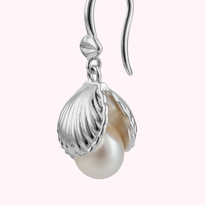 Close up image of a sterling silver shell shaped drop earring with freshwater pearls.