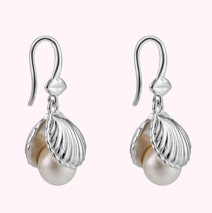 Angle image of a pair of sterling silver shell shaped drop earrings with freshwater pearls.