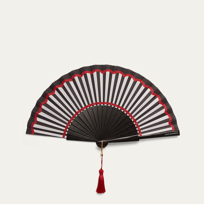 Black and white striped hand fan with red accents on a light gray background