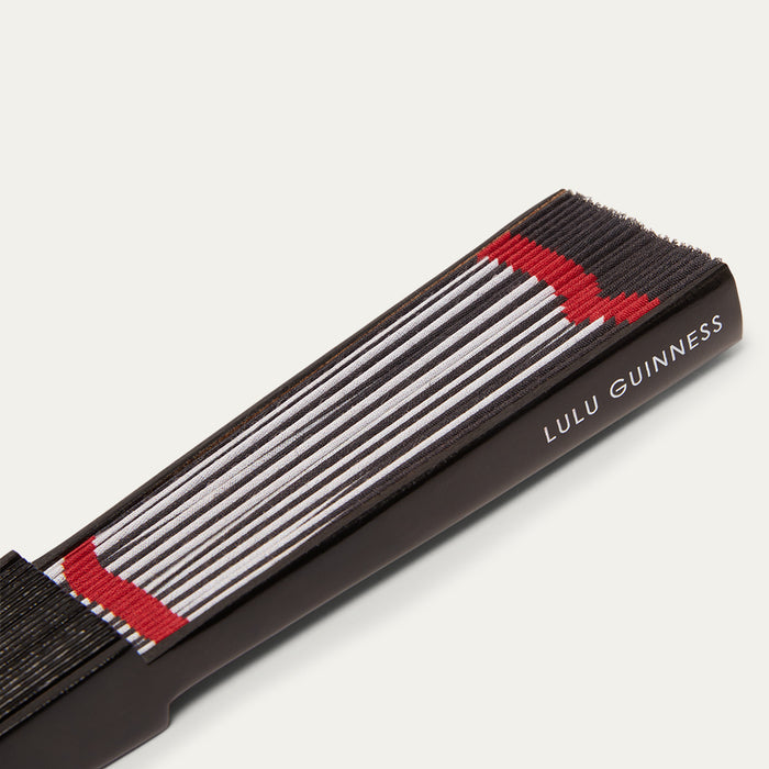 Lulu Guinness close-up image of a handheld fan with black, red, and white stripes on a white background