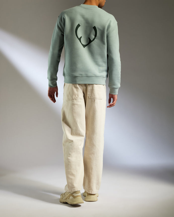 a man wearing a green sweater and white pants