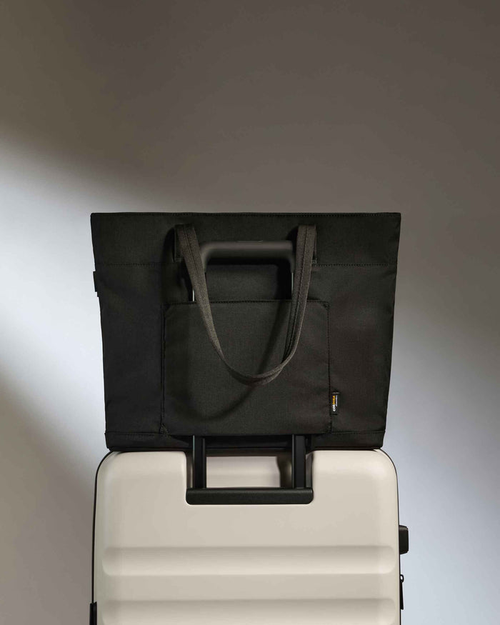 a black bag on top of a white suitcase