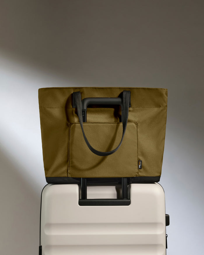 a green bag on top of a white suitcase