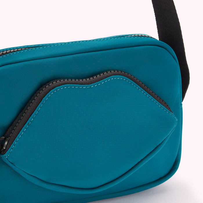 Close-up of a teal crossbody bag with a lip-shaped zipper pocket.