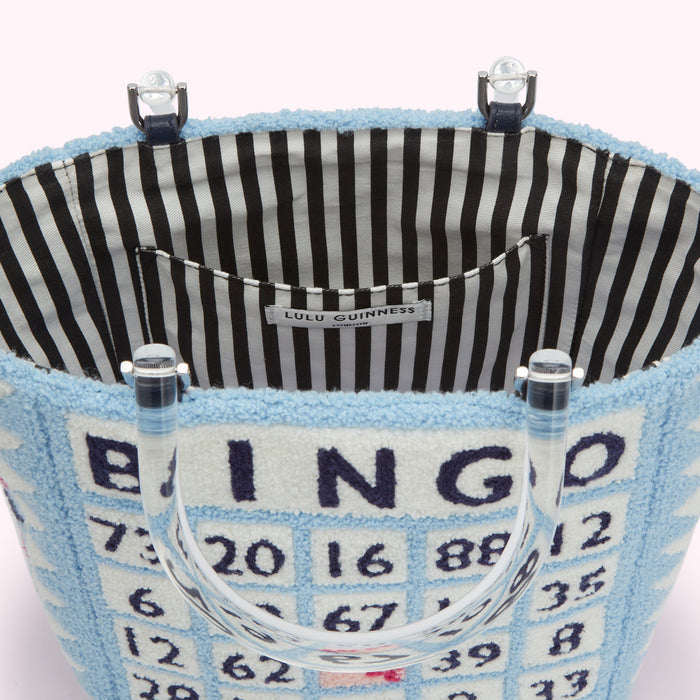 Interior of a light blue Lulu Guinness Bingo tote bag with clear acrylic handles and a black and white striped lining.