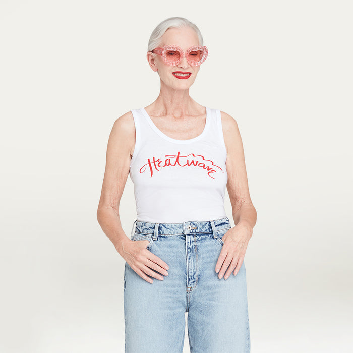 Person wearing a white tank top with red 'Heatwave' text and light blue jeans on a plain background