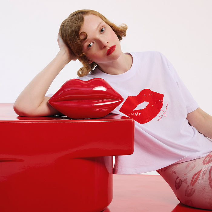 Person wearing a white t-shirt with a red lip print design on a plain